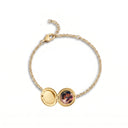 Gold locket bracelet resting on a speckled ceramic plate

