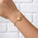 Woman wearing the gold Forever In My Heart Locket Bracelet with the heart locket closed on her wrist
