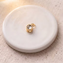 Minimalist Projection Charm in gold on a round dish