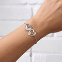 Silver heart photo locket bracelet worn open on a wrist, showing the hidden photo inside
