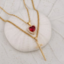 Heart & Sword Couple's Necklace in gold displayed on a shell
