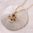 Gold four photo heart locket unfolded into a clover of photo hearts, resting on a textured ceramic dome
