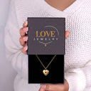 Woman holding a Love Jewelry gift box with the gold Birthstone Heart Locket Necklace inside

