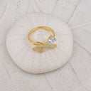 Tiny Bow Tie Ring in gold on a shell