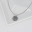 Silver fingerprint necklace on a white dish