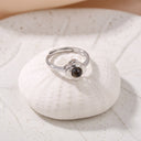 Eternal Flower Projection Ring in silver on a shell