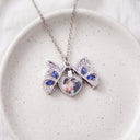 Butterfly Custom Photo Locket (open) in silver, on a ceramic plate