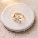 Tiny Bow Tie Ring in gold on a round dish
