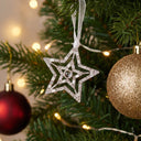 Shiny Star Projection Christmas Ornament on a decorated Christmas tree