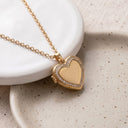 Gold Sparkling Heart Locket Necklace on a speckled ceramic plate, heart locket closed
