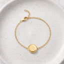 Gold Always With You Locket Bracelet on a speckled ceramic plate with adjustable chain visible
