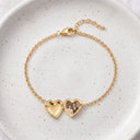 Gold heart photo locket bracelet open to show a personalised photo, displayed on a speckled ceramic plate

