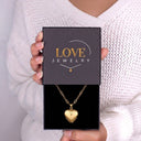 Woman holding a Love Jewelry gift box with the gold All My Hearts Locket Necklace inside
