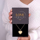 Woman holding a Love Jewelry gift box with the gold Sparkling Heart Locket Necklace inside
